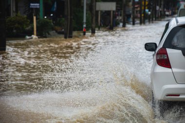 Şiddetli rüzgar ve fırtına dalgaları sonrasında sel sularıyla dolu yolda giden araba yol boyunca akar..