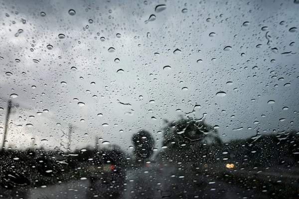 Regendruppels op het autoruit tijdens het rijden door hevige regen- en stormvloeden. — Stockfoto