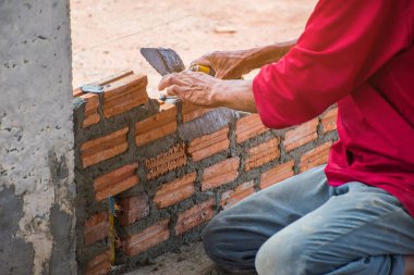İnşaat işçisi dış duvarlar için çimentoya tuğla yerleştiriyor..
