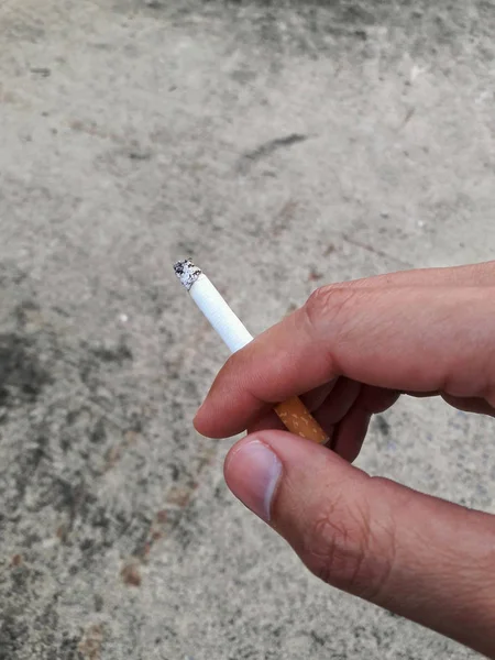 Cigarette pick by hand with concrete background. — Stock Photo, Image
