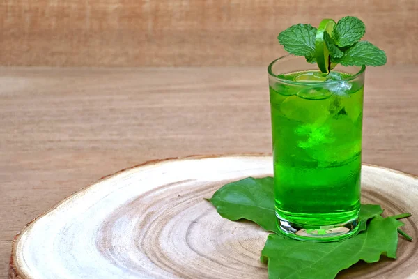 Холодный и освежающий лайм и мятная зеленая вода в стакане с ломтиком лайма и мятным листом на деревянном фоне . — стоковое фото