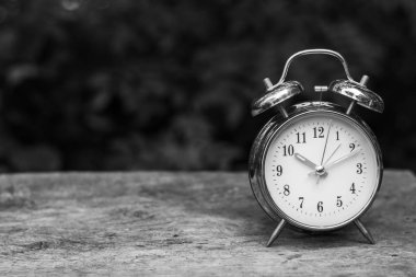 Ahşap masa üzerinde siyah-beyaz alarm saati. Arka planı bulanık ve alanı kopyala.