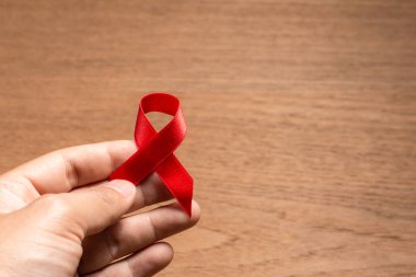 El ele tutuşan kırmızı kurdele Dünya HIV / AIDS Günü için farkındalık yarattı.