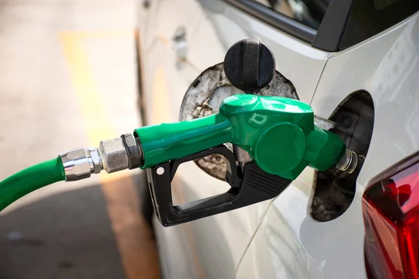 White car refueling at gas station with green fuel nozzle. — Stock Photo, Image