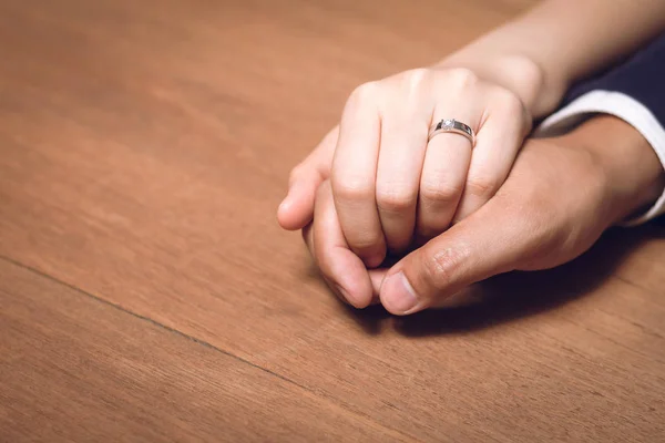 Bruid en bruidegom hand in hand met trouwring op houten tafel. — Stockfoto