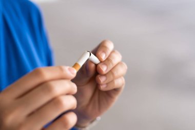 Kadın elleri sigarayı bırakmak için sigarayı tutuyor ve kırıyor. Sağlık konsepti için sigara içmeyi bırak..