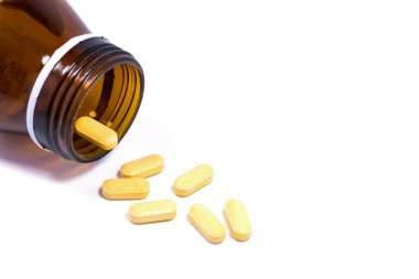 İlaç şişesi beyaz arka plana ilaç ya da vitamin döküyor..