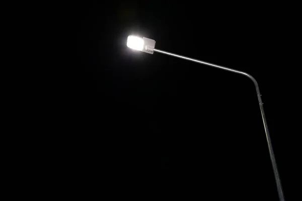Street light LED on steel pole shining at night.