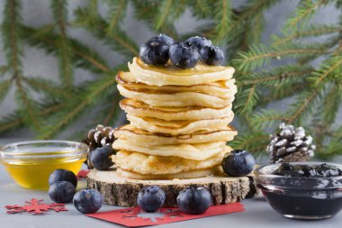 Mavi arka planda yabanmersini, bal ve yaban mersini reçeli ve noel ağacı dallı leziz krepler..