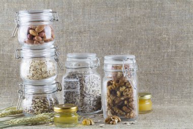 ayçekirdeği, keten tohumu, bal, fındık ve buğday. Sağlıklı yiyecekler cam kavanozlarda çuval bezi üzerinde.