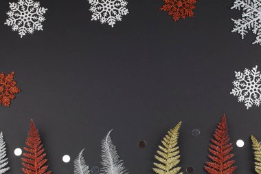 Noel ya da kış kompozisyonu. Beyaz ve kırmızı kar taneleri, siyah arkaplanda çok renkli ağaç dalları.