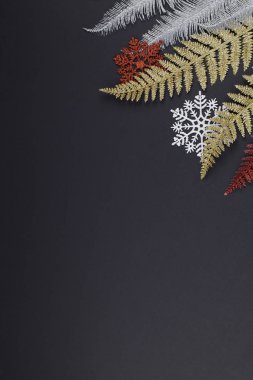 Noel ya da kış kompozisyonu. Beyaz ve kırmızı kar taneleri, siyah arkaplanda çok renkli ağaç dalları.