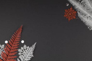 Noel ya da kış kompozisyonu. Beyaz ve kırmızı kar taneleri, siyah arkaplanda çok renkli ağaç dalları.