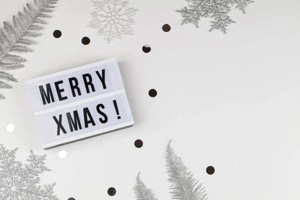 Весёлые рождественские слова на светлой коробке с белыми снежинками, серебряными ветвями деревьев на белом фоне — стоковое фото