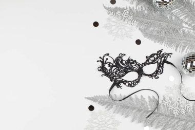 Güzel karnaval siyah maskesi, beyaz kar taneleri, gümüş ağaç dalları ve beyaz arka planda noel süsü. .