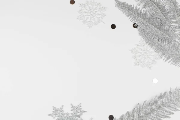 Рождественская композиция с серебряными ветками елки, снежинки на белом фоне — стоковое фото