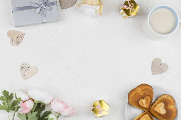 Cupcakes muotoinen sydän, koristelu, lahja, teetä ja kukkia valkoisella taustalla. Ystävänpäivä tausta . — kuvapankkivalokuva