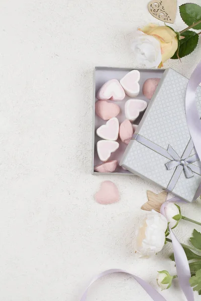 Valkoinen ja vaaleanpunainen karkkia muodossa sydämet laatikko, kukkia, koristelu, lahjoja ja nauha valkoisella pohjalla . — kuvapankkivalokuva