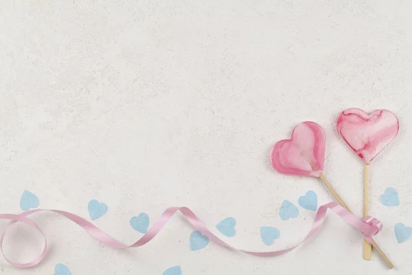 롤리팝 캔디가 하얀 배경에 파란색 하트와 핑크 색 리본을 묶는 모습. — 스톡 사진