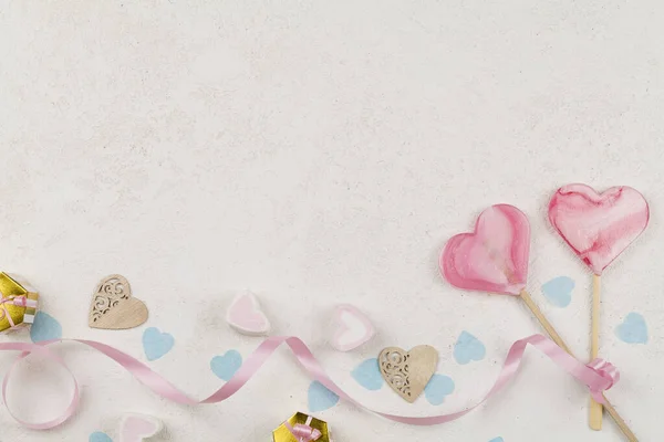 To lyserøde hjerter som slikkepind slik bundet lyserødt bånd med blå hjerter rundt og dekoration på hvid baggrund . - Stock-foto