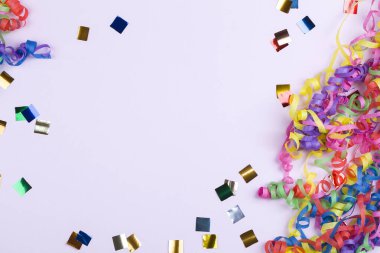 Renkli spiral şeritler ve pembe arka plandaki konfetilerden oluşan şenlikli parti kenarı veya çerçeve