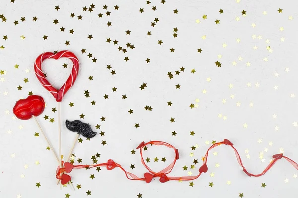 Red and black lollipop in shape of heart, lip and mustache on white background with golden stars. — 스톡 사진