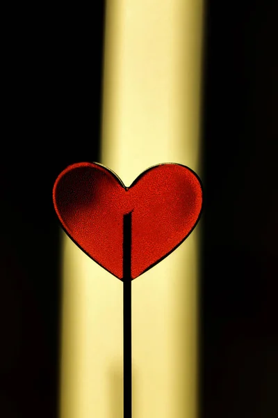 Red heart as lollipop candy on yellow and black background. Valentines day minimalist background — Stock Photo, Image