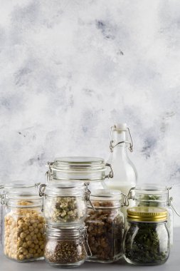 fasulye, keten tohumu, ceviz, süt, cam kasede fiyonk. Mavi arka planda cam kavanozlarda sağlıklı yiyecekler.