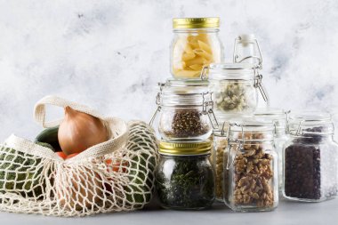 fasulye, keten tohumu, ceviz, süt, fiyonk, cam kasede makarna. Mavi arka planda cam kavanozlarda sağlıklı yiyecekler.