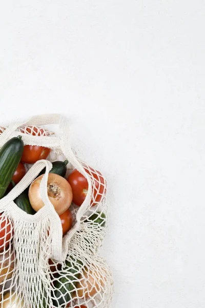 Bolsa de compras de malla blanca con tomates rojos, lazo y pepinos verdes sobre fondo blanco . —  Fotos de Stock