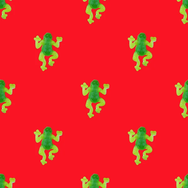 pattern with green frogs candy on red background. Flat lay, top view, view from above. Photographic collage and seamless pattern