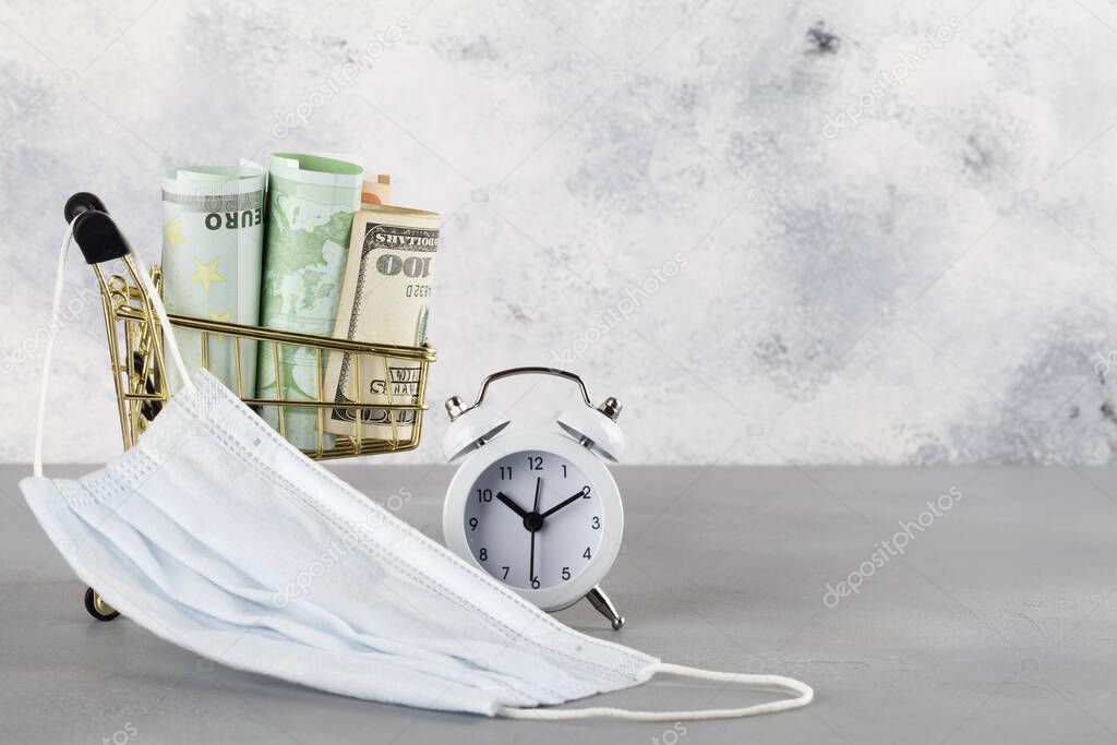 white retro alarm clock and dollars, euro in shopping cart with medical mask on blue background. Shopping time, Market, Consumer Concept. copy space