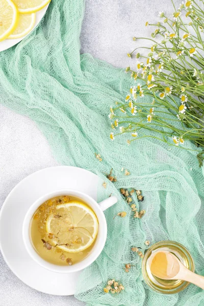 herbal chamomile tea, honey, lemon and fresh daisy flowers on blue background. doctor treatment and prevention of immune concept, traditional medicine. top view flat lay