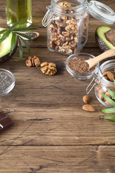 健康脂肪来源亚麻坚果油鳄梨籽和苦味巧克力背景棕色木材 健康食品生态概念 复制空间 — 图库照片