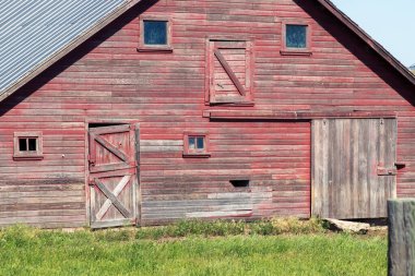 A large barn with grass in front of a house