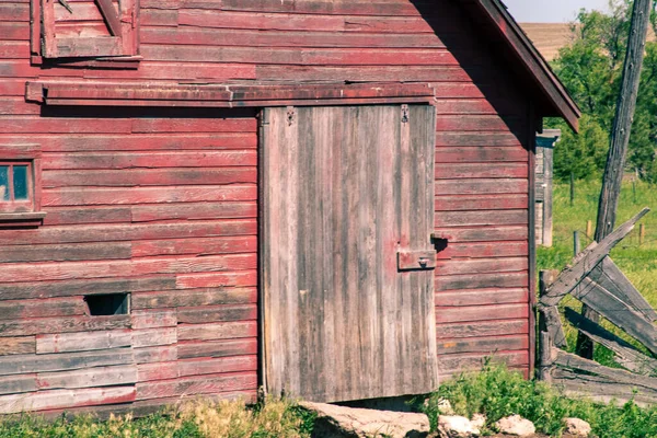 Front of an old abandoned red barn with door and sliding door — Stockfoto