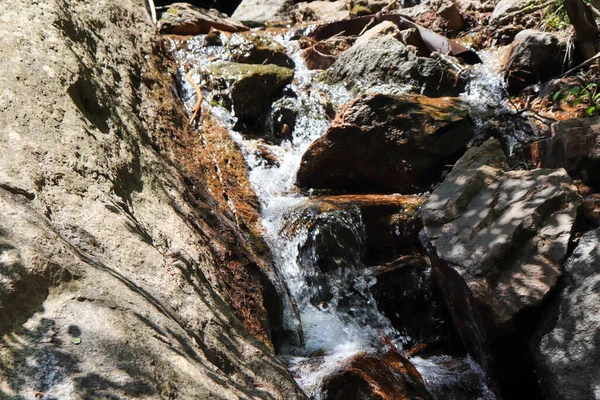 Uma pequena cachoeira sobre um penhasco rochoso — Fotografia de Stock