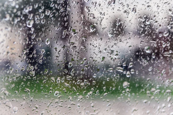 Gotas de lluvia en el cristal de una ventana, edificios borrosos en el fondo . — Foto de Stock