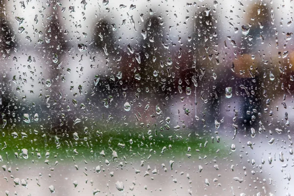 Gotas de lluvia en el cristal de una ventana, edificios borrosos en el fondo . — Foto de Stock
