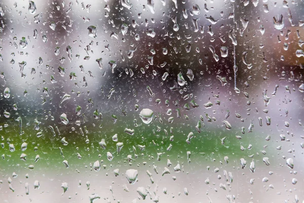 Капли дождя на оконное стекло, размытые здания на заднем плане . — стоковое фото