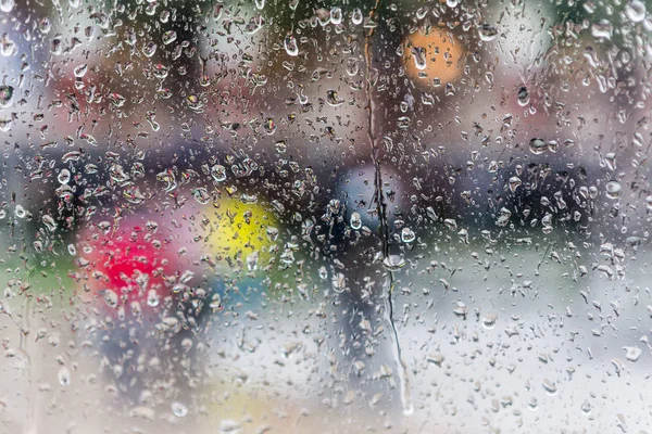 Gotas de lluvia en el cristal de una ventana, edificios borrosos en el fondo . — Foto de Stock