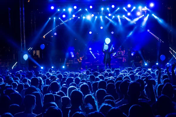 Parlak sahne ışıkları önünde konser kalabalığının siluetleri — Stok fotoğraf