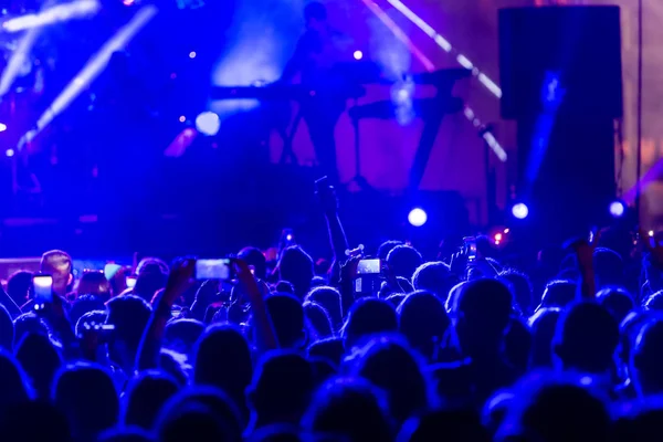 Parlak sahne ışıkları önünde konser kalabalığının siluetleri — Stok fotoğraf