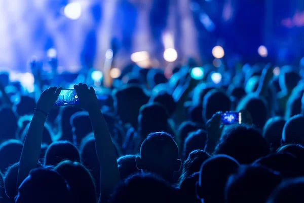 Parlak sahne ışıkları önünde konser kalabalığının siluetleri — Stok fotoğraf