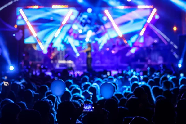 Parlak sahne ışıkları önünde konser kalabalığının siluetleri — Stok fotoğraf