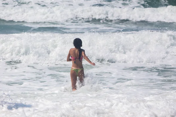 Неузнаваемый молодой человек в море играет с волнами — стоковое фото