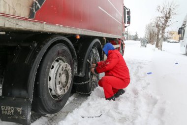 Sürücüler üzerinde onların lastikleri altında ağır zincirleri yüklemeye çalıştığınız 