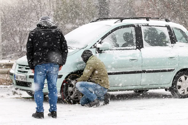 Drivers are trying to install chains on their tyres under heavy — Stock Photo, Image