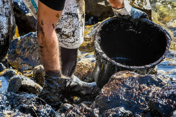 Försöka rensa upp olja som har spolats iland, på en strand o — Stockfoto