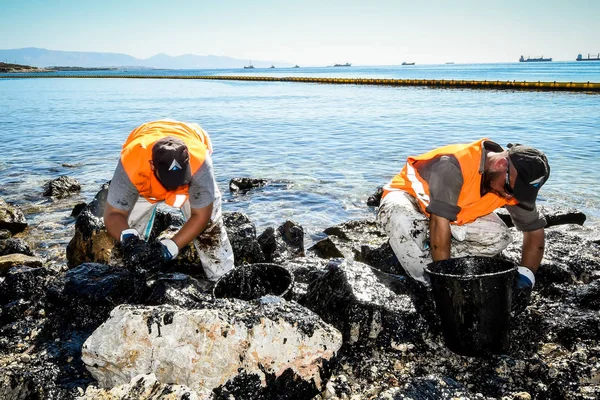 Trabalhadores tentam limpar o óleo que foi lavado em terra, em uma praia o — Fotografia de Stock